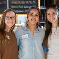 Three event attendees standing together and smiling for photo